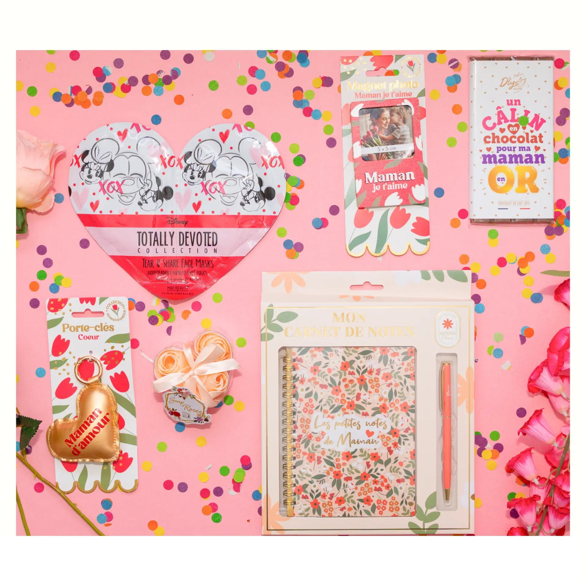 Disposition à plat des articles de la box maman incluant une tablette de chocolat blanc, un carnet de notes et un porte-clés coeur doré.