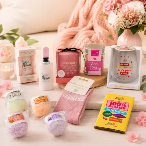 Box maman déballée sur une table en bois avec bougie allumée, bouquet de fleurs roses et plaid cocooning en arrière-plan.