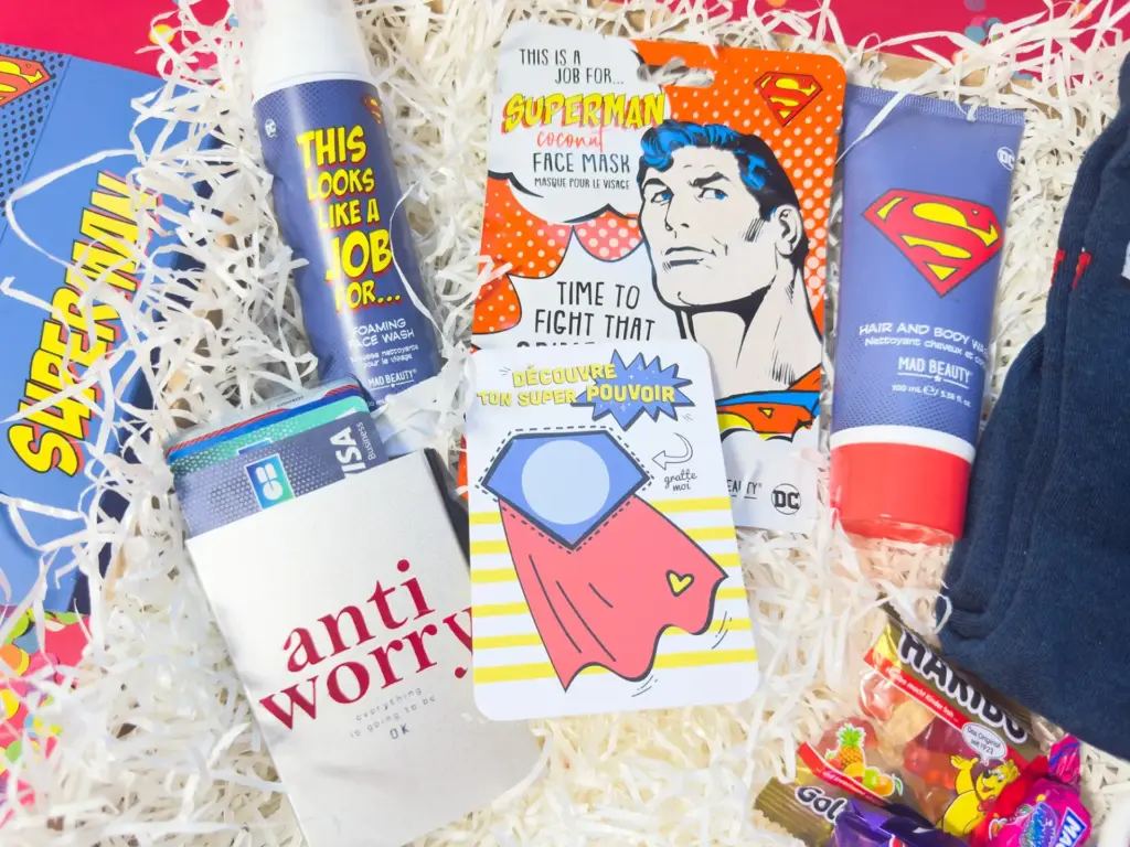 Coffret cadeau homme original comprenant savon pour cheveux et corps, mousse nettoyante visage, chaussettes Super Man, bonbons, carte à gratter ‘Super toi’ et porte-cartes original – idée cadeau homme unique et originale.