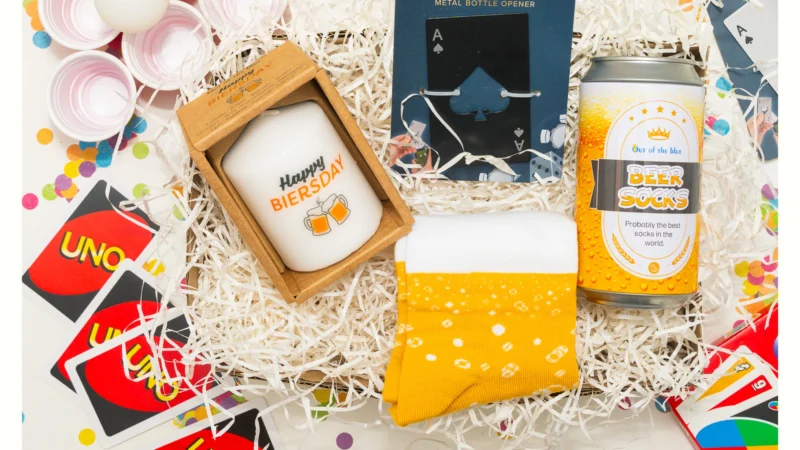 Box anniversaire homme avec bougie 'Happy Biersday', ouvre-bouteille original carte As, chaussettes dans un emballage de biĂšre et jeu Ă  boire.
